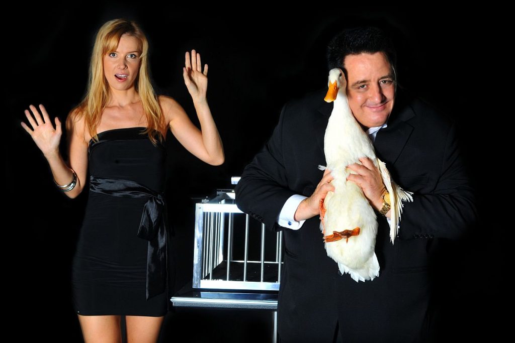 Joe Conrad Illusionist holding a duck with his female assistant.